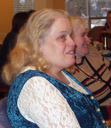 Anna in a beautiful teal blue dress with lace sleeve sitting with Zandra at their table