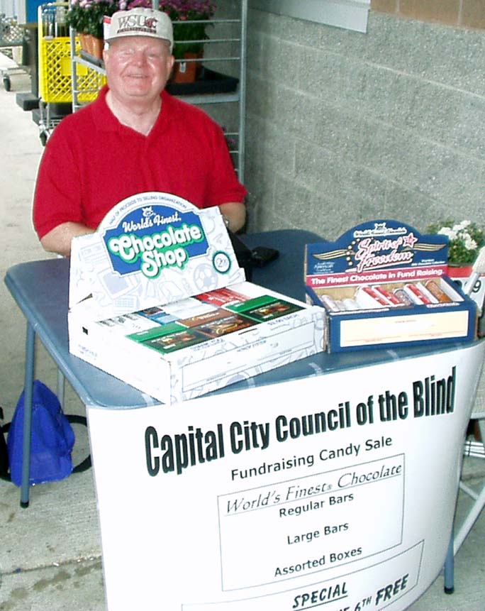 Berl sitting at a card table selling candy.